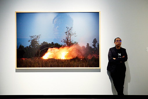 アピチャッポン・ウィーラセタクン。『ゴースト・ティーン』が『炎』にうっすら映っている。各作品が関係し合うような展示レイアウトが特徴的 /『炎』2009年 インクジェット・プリント 東京都写真美術館蔵