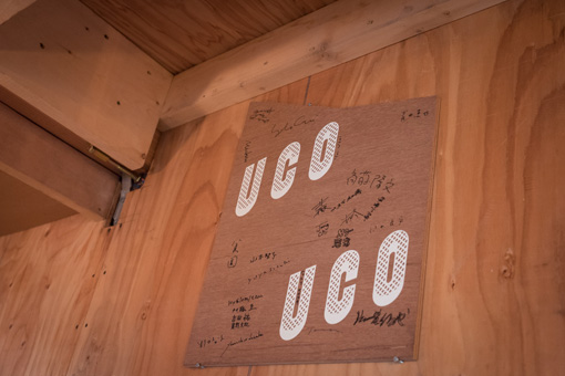 過去の参加アーティストのサインが書かれた店内に掲げられたUCOの看板